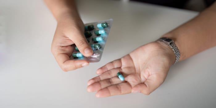 Close up woman holding pill in hand with water. Female take tablet from headache, painkiller, Healthcare, medicine, treatment. therapy concept.