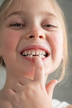 A cute little girl smeared in chocolate eats cookies while lying on the sofa. Vertical photo