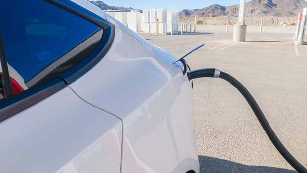 Baker, California, USA-December 3, 2022-During the day, a Tesla vehicle is seen charging at a Tesla Supercharging station, utilizing the high-speed charging infrastructure for convenient and efficient electric vehicle refueling.