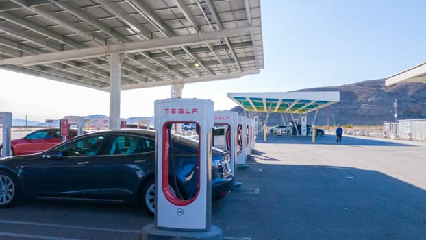 Baker, California, USA-December 3, 2022-During the day, a Tesla vehicle is seen charging at a Tesla Supercharging station, utilizing the high-speed charging infrastructure for convenient and efficient electric vehicle refueling.