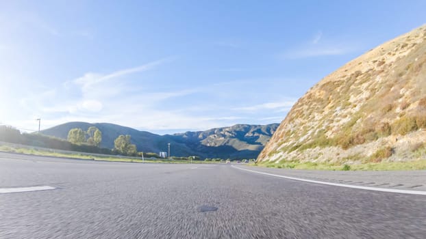 Under a clear blue sky, driving on HWY 101 near California's El Capitan State Beach during the day offers captivating views of the scenic coastal surroundings.