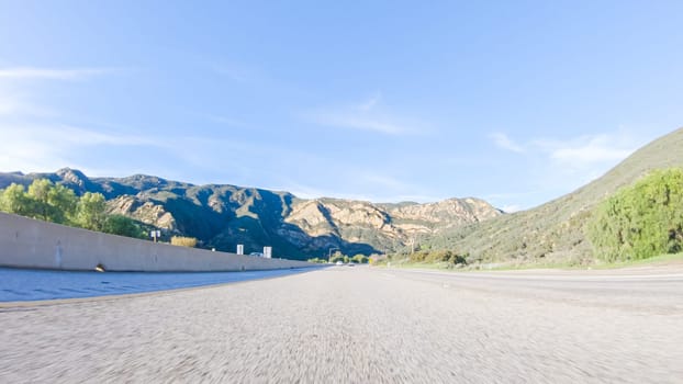 Under a clear blue sky, driving on HWY 101 near California's El Capitan State Beach during the day offers captivating views of the scenic coastal surroundings.