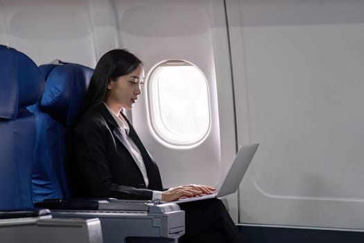 Asian young woman using laptop at first class on airplane during flight, Traveling and Business concept.