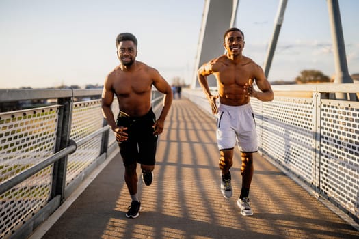 Two friends are jogging on the bridge in the city.