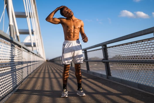 Young  man is exercising on the bridge in the city. He is stretching his body.