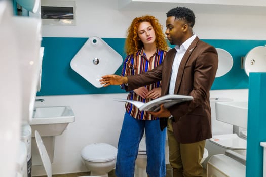 Businessman owns small business bath store. He is talking with a customer who is choosing the goods.