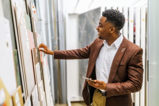 Portrait of buyer in bathroom store. Man is choosing tiles for his apartment.