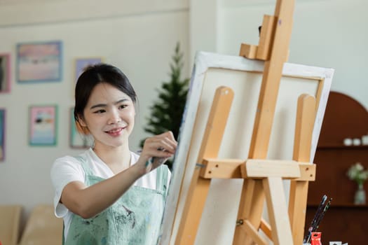beautiful young woman artist working on painting something on a large canvas.