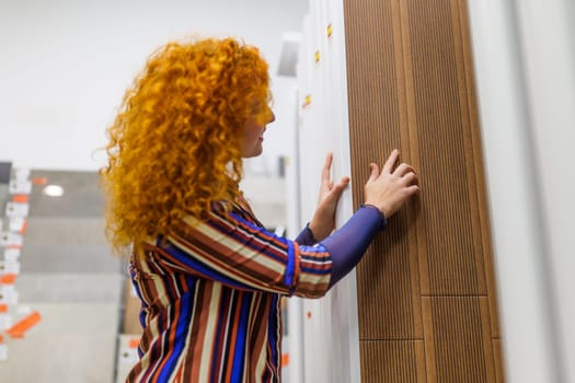 Portrait of buyer in bathroom store. Redhead woman is choosing tiles for her apartment.