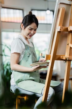 beautiful young woman artist working on painting something on a large canvas.