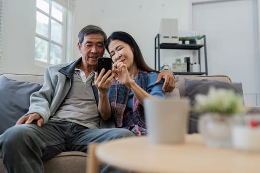 Retired elderly couple looking at mobile phone together, shopping online.