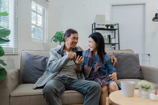 Retired elderly couple looking at mobile phone together, shopping online, surfing website together.