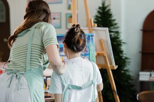 beautiful young woman artist working on painting something on a large canvas.