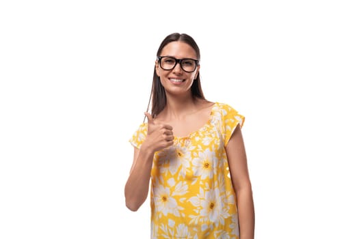 a young woman dressed in a yellow sundress wears glasses for vision correction.