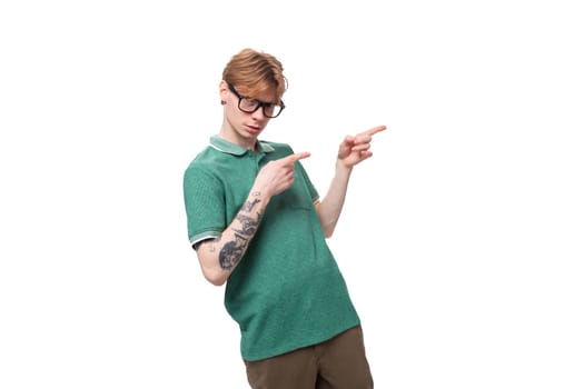 young caucasian man with red hair dressed in a green t-shirt smiling and joking against the background with copy space.