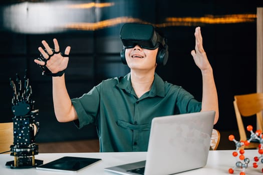 In a classroom Asian teenager uses VR glasses to experiment with a robot arm project. Integrating robotics programming with STEM education embracing futuristic technology. moves a robotic hand