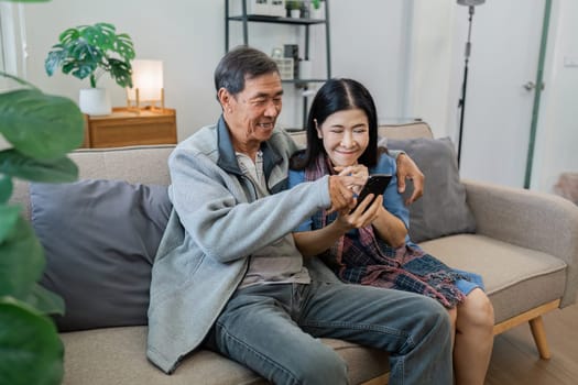 Retired elderly couple looking at mobile phone together, shopping online, surfing website together.