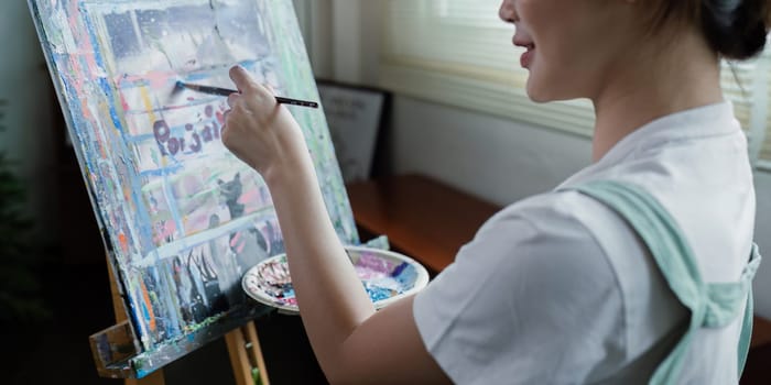 beautiful young woman artist working on painting something on a large canvas.