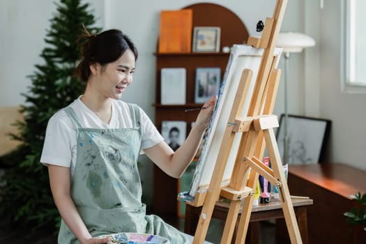 beautiful young woman artist working on painting something on a large canvas.