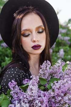 A fashionable girl with dark hair, a spring portrait in lilac tones in summer. Bright professional makeup