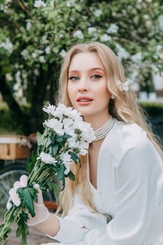 A blonde girl with long hair on a walk in a spring park. Springtime and blooming apple trees