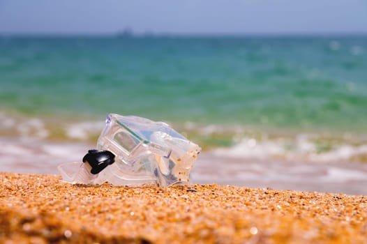 Shallow depth of field snorkeling mask lies on a sandy beach overlooking the sea and sky, no people.