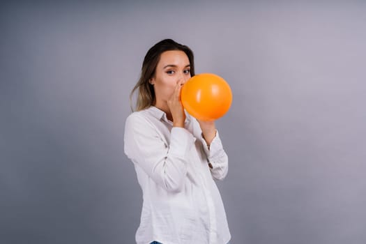 Portrait of beautiful woman with ballon in hands on grey background in studio