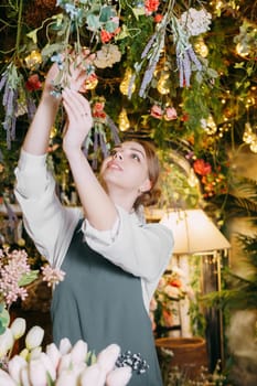 A woman in her florist shop collects bouquets of flowers. The concept of a small business. Bouquets of tulips for the holiday on March 8