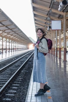 Young Asian woman in modern train station Female backpacker passenger waiting for train at train station to go on holiday..