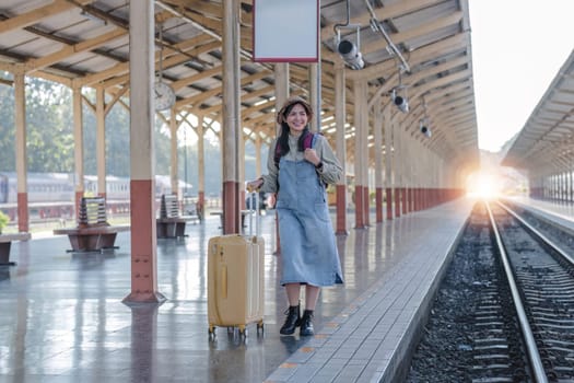 Young Asian woman in modern train station Female backpacker passenger waiting for train at train station to go on holiday..