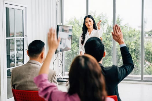 A seminar classroom hosts a large group actively engaging in the discussion, raising their hands. The answers are ready within this dynamic conference audience.