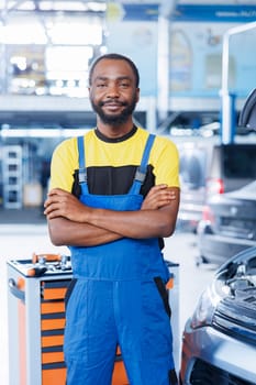 Portrait of proud BIPOC serviceman in auto repair shop tasked with changing cars oil. Licensed specialist in garage ready to start doing checkups on vehicles in garage workspace