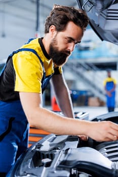 Car service mechanic expertly examines engine using advanced mechanical tools, ensuring optimal automotive performance and safety. Seasoned garage expert conducts annual vehicle checkup