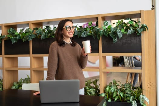 Businesswoman drink coffee waiting colleagues in meeting room, female executive professional entrepreneur using laptop corporate software doing paperwork at workplace drinking coffee