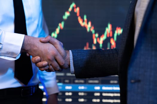 Investor stock trading of business partners shaking hands against screen for cooperating of investing agreement of highest valued technology product trending on the dynamic market stock. Sellable.