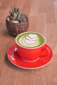 matcha latte in a red color cup on table .