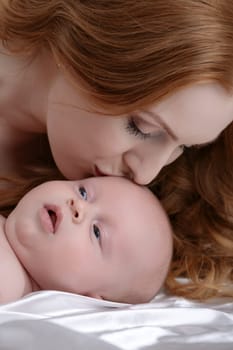 Portrait of beautiful mother kisses her adorable little son