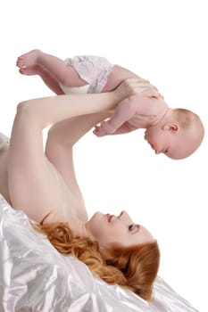 Happy red-haired mother hold baby over her head. Isolated on whte backdrop