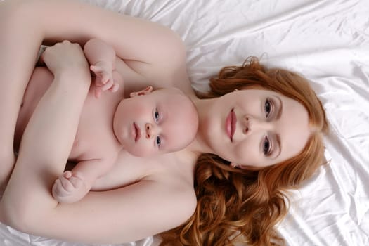 Top view of happy red-haired mother holds her child on chest