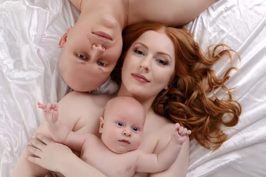 Top view of happy young parents with adorable baby