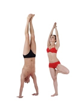 Yoga. Man doing handstand and woman stand on one leg