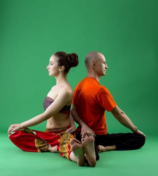Shot of paired yoga training in studio, on green background