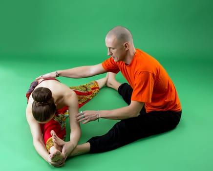 Joint yoga workout with experienced trainer. Studio photo, on green background