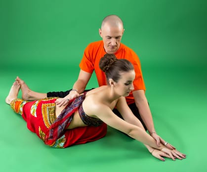 Yoga. Experienced coach helps woman to perform asana