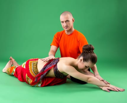 Yoga. Studio photo of instructor helps woman to perform asana