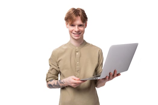young handsome redhead student man holding a gray laptop for work.