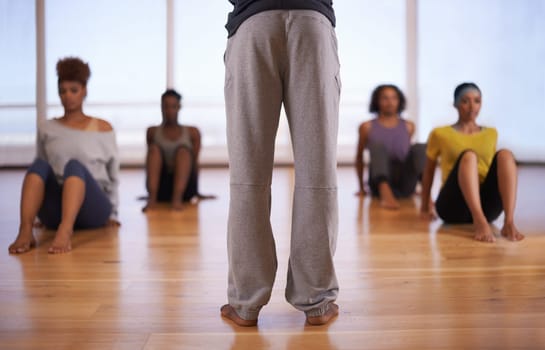 People, dancer and personal trainer with class of student in fitness, workout or pilates at the studio. Rear view of instructor talking to group in body warm up or stretching for health and wellness.