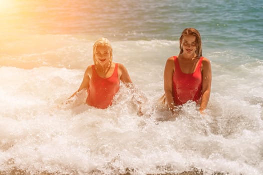 Women ocean play. Seaside, beach daytime, enjoying beach fun. Two women in red swimsuits enjoying themselves in the ocean waves