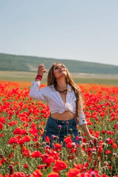 Happy woman in a poppy field in a white shirt and denim skirt with a wreath of poppies on her head posing and enjoying the poppy field