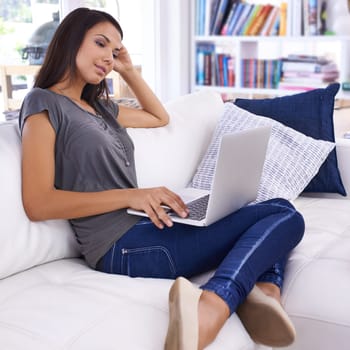Woman, laptop and online in home for relax with typing email, communication and internet research in living room. Person, technology and social media search, web subscription or writing blog on couch.